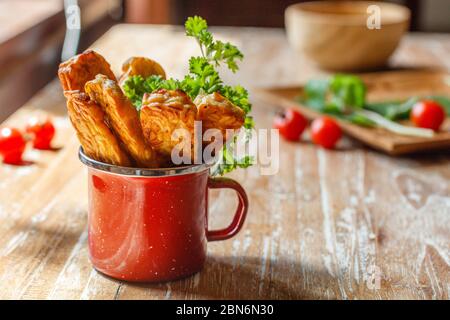 Rot emaillierter Becher mit gebratenem Tempeh (traditionelles indonesisches Sojaprodukt) auf Holzoberfläche. Seitenansicht. Mit Platz. Stockfoto