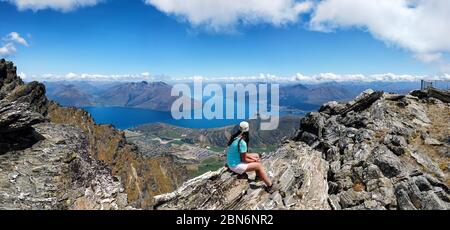 Wanderer sitzt auf Felsen der Remarkables Bergkette, Queenstown, Otago, South Island, Neuseeland, Ozeanien. Stockfoto