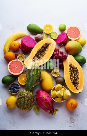 Tropisches Fruchtmuster mit Mango, Papaya, Pitahaya, Passionsfrucht, Trauben, Limetten und Ananas. Tisch mit Zutaten für Sommernaschen auf Beton Stockfoto