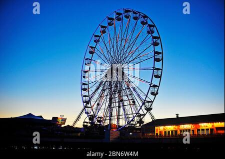 Das leere beleuchtete Riesenrad am Central Pier in der Abenddämmerung im Frühling während der Coronavirus-Sperre, die eine geschäftige Zeit sein sollte Stockfoto