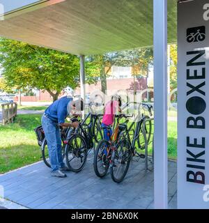 Die gutgelaunte Familie nutzt ein vorbildliches Fahrradparkkonzept für einen Stadtbummel zu Fuß Stockfoto