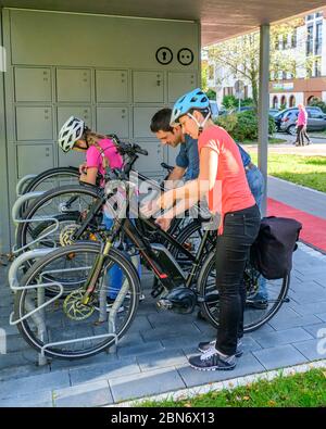 Die gutgelaunte Familie nutzt ein vorbildliches Fahrradparkkonzept für einen Stadtbummel zu Fuß Stockfoto