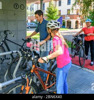 Die gutgelaunte Familie nutzt ein vorbildliches Fahrradparkkonzept für einen Stadtbummel zu Fuß Stockfoto