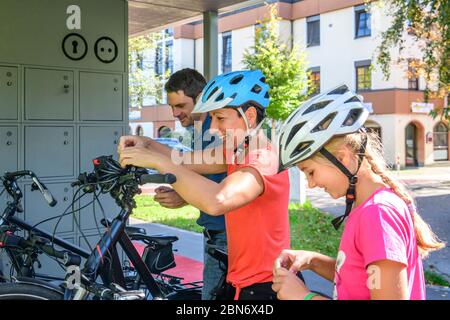 Die gutgelaunte Familie nutzt ein vorbildliches Fahrradparkkonzept für einen Stadtbummel zu Fuß Stockfoto