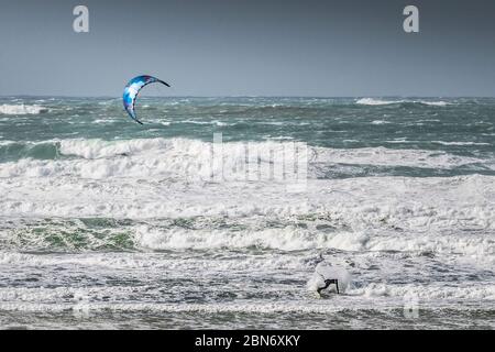 Ein einsamer Kitesurfer, der den starken Wind von Storm Jorge in Fistral in Newquay in Cornwall genießt. Stockfoto