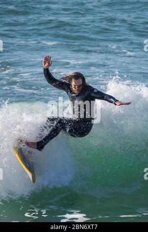 Spektakuläre Action als männlicher Surfer auf einer Welle im Fistral in Newquay in Cornwall reitet. Stockfoto