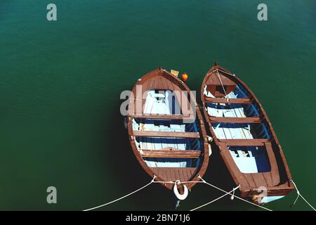 Zwei kleine braune blaue Holzboote auf ruhigem grünen Meerwasser, Kreta, Griechenland Stockfoto