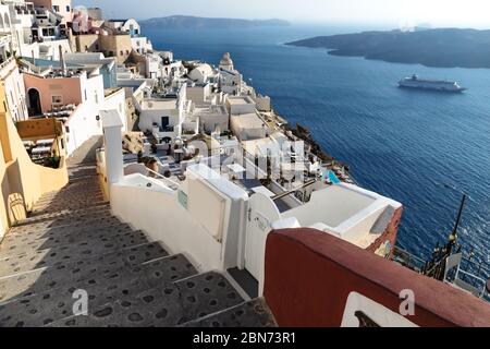 Treppe in einem typisch griechischen Dorf mit Kirchturm an einem sonnigen Tag, weit über dem blauen Meer, Fira, Santorini, Griechenland Stockfoto