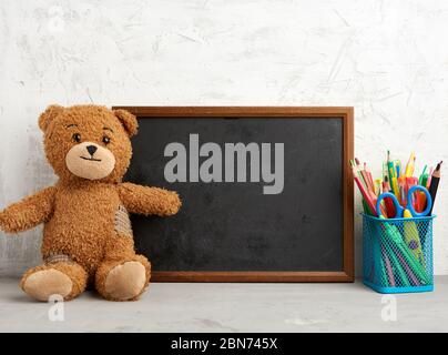 Brauner Teddybär und leerer rechteckiger Holzrahmen, Kreidetafel zum Schreiben einer To-do-Liste. Zurück zur Schule Stockfoto