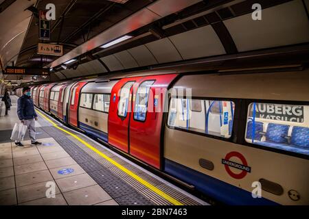 London, Großbritannien. Mai 2020. Ein maskierter Mann und eine Frau warten auf einen leeren Northern Line Train - die Passagierzahlen bleiben dramatisch in der U-Bahn, auch während der Hauptverkehrszeit und sogar am ersten Tag der Lockerung der Regierungsführung. Wer reist, versucht, der Anleitung auf 2m soziale Distanz zu folgen und vielleicht etwa die Hälfte tragen Masken - trotz der Anordnungen des Londoner Bürgermeisters, dass er erwartet, dass jeder eine Maske im öffentlichen Verkehr trägt. Die "Lockdown" geht weiter für den Ausbruch des Coronavirus (Covid 19) in London. Kredit: Guy Bell/Alamy Live News Stockfoto