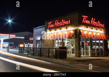 Tim Hortons Store, die beliebte kanadische Café-Kette, die man nachts sieht, wurde gedreht, als ein Auto die Drive￼-Thru-Linie verlässt. Stockfoto