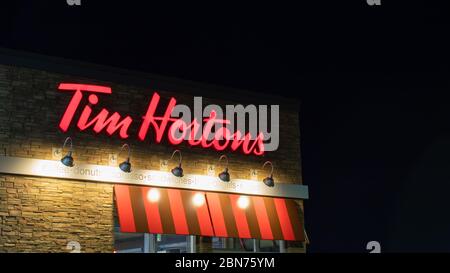 Tim Hortons Schild, eine berühmte kanadische Kaffee- und Fast-Food-Restaurantkette, die man nachts an einem Ort sieht. Stockfoto