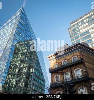 Alt und Neu. Kontrastierende architektonische Stile im Zentrum Londons mit einem abstrakten kantigen Büroblock, der sich gegen einen traditionellen alten Pub ansetzt. Stockfoto