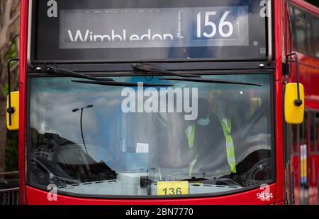 Wimbledon, London, Großbritannien. 13 Mai 2020. Am 51. Tag der Sperrung des Coronavirus in Großbritannien werden einige Unternehmen wieder eröffnet und Arbeiter, die nicht von zu Hause aus arbeiten können, werden ermutigt, wenn möglich mit dem Fahrrad oder zu Fuß zur Arbeit zu reisen. Busfahrer mit Gesichtsmaske am Busbahnhof Wimbledon. Quelle: Malcolm Park/Alamy Live News. Stockfoto