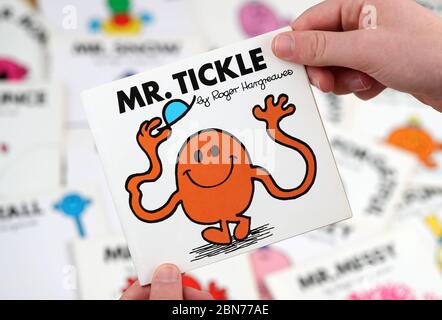Ein Junge, der das Buch Mr Men lesen möchte, Mr Tickle von Roger Hargreaves Stockfoto
