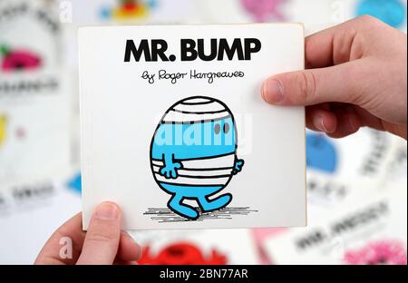 Ein Junge, der das Buch Mr Men lesen möchte, Mr. Bump von Roger Hargreaves Stockfoto