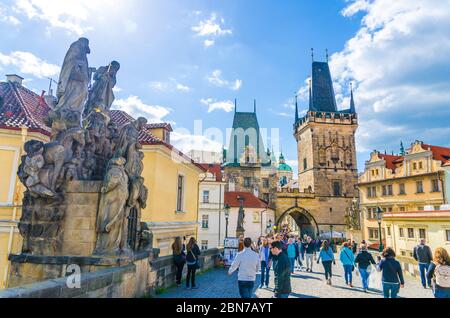 Prag, Tschechische Republik, 13. Mai 2019: Menschen gehen auf Kopfsteinpflaster Fußgänger Karlsbrücke Karluv meisten über Moldau, Brücke Statue und Turm Malostranska vez Hintergrund Stockfoto