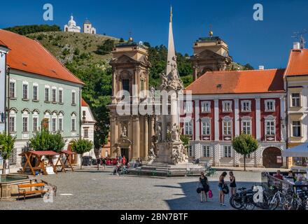 Pestsäule der Heiligen Dreifaltigkeit, Dietrichstein-Grab dahinter, St. Sebastian-Kapelle auf dem Heiligen Hügel in der Ferne, in Mikulov, Mähren, Tschechische Republik Stockfoto