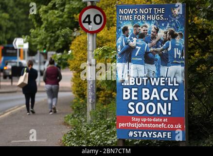 Die Leute gehen an einem Schild vorbei, das sagt: "Jetzt ist nicht die Zeit für Umarmungen ... aber wir werden bald wieder kommen!" Außerhalb des McDiarmid Park, dem Heimstadion von St Johnstone. Stockfoto