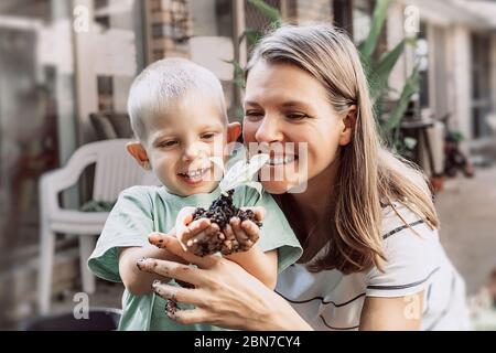 Junge Pflanze sprießt in den Händen des kleinen Jungen. Lächelnde Mutter und Sohn. Konzept der Landwirtschaft und des Umweltschutzes. Stockfoto