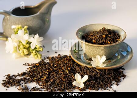 Trockene grüne Teekräuter mit Blumen und Vintage Porzellanteller und Milchkrug auf weißem Hintergrund. Stockfoto