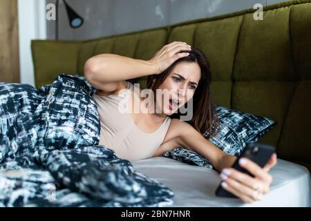 Attraktive junge Frau verpasste das Klingeln des Weckers und haben das Erwachen verschlafen und sind spät, reagierend in Schrecken zu der Zeit. Lustige Gesichtsausdruck Stockfoto