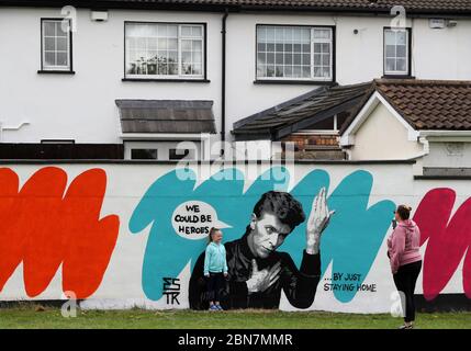 Lorna Mullins und ihre Tochter Penny Mullins (6) fotografieren mit der irischen Künstlerin Emmalene Blake das Wandbild von David Bowie in Süd-Dublin. Dies ist das jüngste in der Serie 'Stay at Home' des Dubliner Künstlers, der die Menschen dazu ermutigt, sich an soziale Distanzierungen zu halten. Andere Künstler waren Dua Lipa, Robyn und Cardi B. Stockfoto