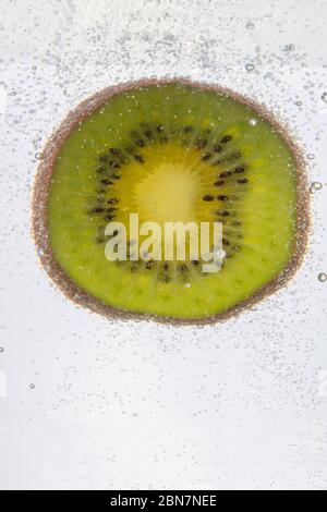 Ein erstaunlicher Schuss von einer Scheibe Kiwi-Frucht, die unter Wasser getaucht ist Stockfoto