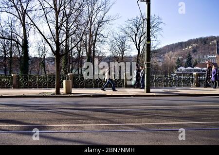 Prag, Tschechische Republik - 30. Dezember 2019: Menschen, die auf einem Bürgersteig in der Nähe einer asphaltierten Straße gehen Stockfoto