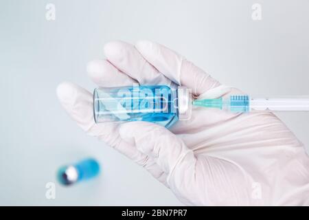 Der Arzt sammelt Medikamente aus einer Ampulle in eine Spritze. Impfstoffflasche Stockfoto