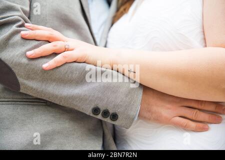 Mann und Frau halten sich an der Taille und zeigen den Hochzeitsring Stockfoto