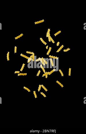 Italienische fliegende rohe Pasta isoliert auf schwarzem Hintergrund. Macaroni fusilli fallen. Stockfoto