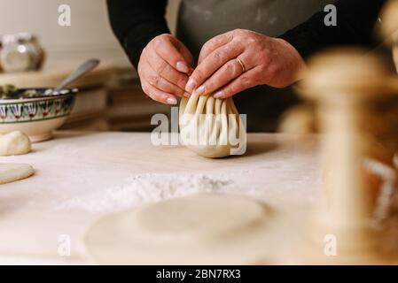 Kochen. Frau, die khinkali für seine Familie macht, Nahaufnahme. Zubereitung georgischen traditionellen Mahlzeit aus Teig und Fleisch in der Küche. Nationale Küche, Kochprozess Konzept. Stockfoto