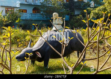 Lumbini, Nepal - 17. November 2016: Der Junge sitzt auf dem Rücken eines Wasserbüffels und spielt Flöte. Skulptur im vietnamesischen Tempel in Lumbini. Stockfoto