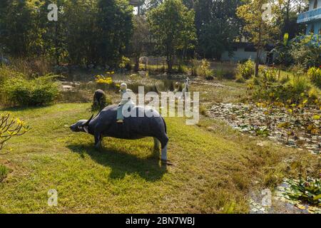 Lumbini, Nepal - 17. November 2016: Skulptur im vietnamesischen Tempel in Lumbini. Der Junge sitzt auf dem Rücken eines Wasserbüffels und spielt Flöte. Stockfoto