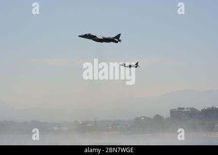 Serie 115 von 165 zwei McDonnell Douglas AV-8B Harrier II's Schwebt und dreht sich mit dem Strand und den Gebäuden dahinter Tag Der Streitkräfte In Santander Stockfoto