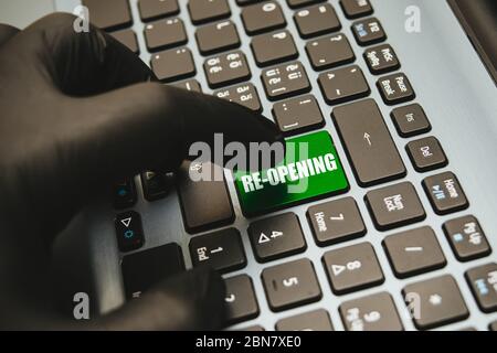 Hand in Handschuhe warten auf die Taste wieder öffnen auf der Tastatur, Konzept für die Wiedereröffnung Geschäft nach Covid-19 Coronavirus Nahaufnahme zu drücken Stockfoto