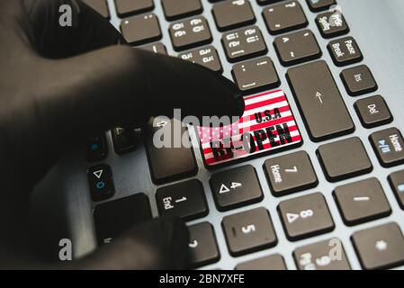 Hand in Handschuhe warten auf die Taste wieder öffnen auf der Tastatur, Konzept für die Wiedereröffnung Geschäft nach Covid-19 Coronavirus Nahaufnahme zu drücken Stockfoto