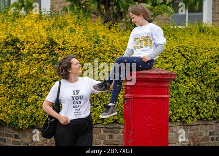 Fiona und ihre Tochter Lola aus London tragen T-Shirts mit dem Slogan: „Wenn Sie dies lesen können, sind Sie zu nahe an COVID“, die vom globalen Unternehmen für die Markenumwandlung FutureBrand als gemeinnützige Initiative ins Leben gerufen wurden, um die wichtigsten Richtlinien für soziale Distanzierung zu stärken, während die Nation aus der Sperrung der Coronavirus-Pandemie herauskommt. Stockfoto