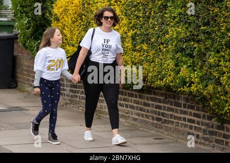 Fiona und ihre Tochter Lola aus London tragen T-Shirts mit dem Slogan: „Wenn Sie dies lesen können, sind Sie zu nahe an COVID“, die vom globalen Unternehmen für die Markenumwandlung FutureBrand als gemeinnützige Initiative ins Leben gerufen wurden, um die wichtigsten Richtlinien für soziale Distanzierung zu stärken, während die Nation aus der Sperrung der Coronavirus-Pandemie herauskommt. Stockfoto