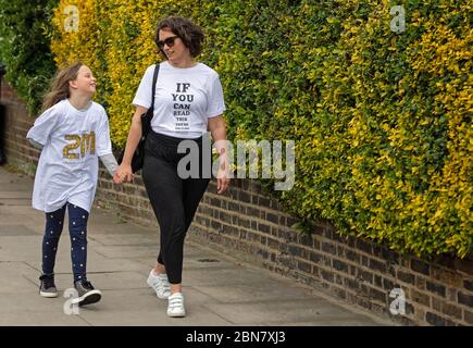 Fiona und ihre Tochter Lola aus London tragen T-Shirts mit dem Slogan: „Wenn Sie dies lesen können, sind Sie zu nahe an COVID“, die vom globalen Unternehmen für die Markenumwandlung FutureBrand als gemeinnützige Initiative ins Leben gerufen wurden, um die wichtigsten Richtlinien für soziale Distanzierung zu stärken, während die Nation aus der Sperrung der Coronavirus-Pandemie herauskommt. Stockfoto