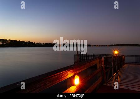 Sonnenuntergang von einem Pier mit Blick auf einen See mit Gators in Orlando, Florida Stockfoto