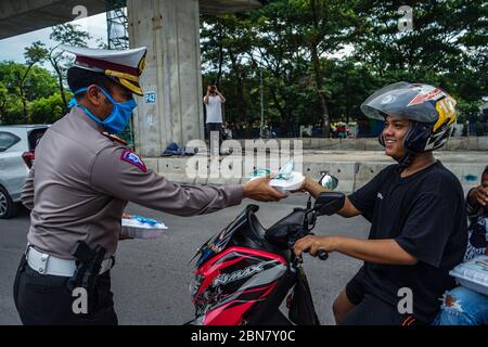 Makassar, Indonesien. Mai 2020. Die Verkehrspolizei Süd Sulawesi verteilt Lebensmittel, um schnell zu brechen, und maskiert Fußgänger und Autofahrer auf den Straßen. (Foto: Herwin Bahar/Pacific Press) Quelle: Pacific Press Agency/Alamy Live News Stockfoto