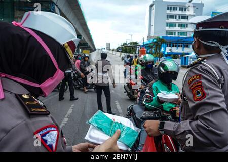 Makassar, Indonesien. Mai 2020. Die Verkehrspolizei Süd Sulawesi verteilt Lebensmittel, um schnell zu brechen, und maskiert Fußgänger und Autofahrer auf den Straßen. (Foto: Herwin Bahar/Pacific Press) Quelle: Pacific Press Agency/Alamy Live News Stockfoto