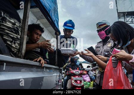 Makassar, Indonesien. Mai 2020. Die Verkehrspolizei Süd Sulawesi verteilt Lebensmittel, um schnell zu brechen, und maskiert Fußgänger und Autofahrer auf den Straßen. (Foto: Herwin Bahar/Pacific Press) Quelle: Pacific Press Agency/Alamy Live News Stockfoto