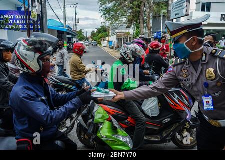 Makassar, Indonesien. Mai 2020. Die Verkehrspolizei Süd Sulawesi verteilt Lebensmittel, um schnell zu brechen, und maskiert Fußgänger und Autofahrer auf den Straßen. (Foto: Herwin Bahar/Pacific Press) Quelle: Pacific Press Agency/Alamy Live News Stockfoto