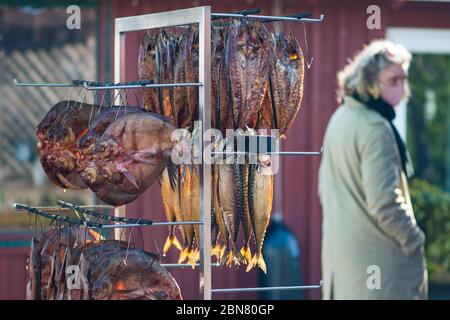 Trocken geräucherte gewürzte Makrele und verschiedene frische Fische in einem Fischmarkt mit Frau Dressing Schutzmaske Stockfoto