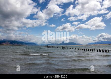 Holzpfosten von einem alten Pier, Puerto Natales, Patagonien, Chile, Cerro Monumento Moore im Hintergrund. Stockfoto