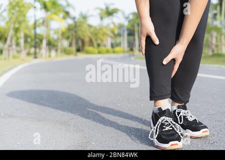 Asiatische Frau verwenden Hände halten Sie auf ihrem Knie Verletzung beim Laufen auf der Straße im Park, Verletzung von Workout-Konzept. Stockfoto
