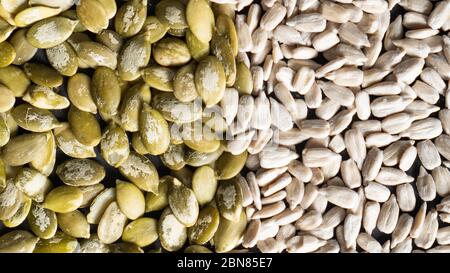 Draufsicht auf verschiedene Samen als Hintergrund. Zwei Teile Sonnenblumen- und Kürbiskerne. Gesunde Ernährung. Textur der Samen Stockfoto